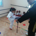 Niña en clase de taekwondo pateando
